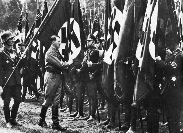 Adolf Hitler consecrating the standards at the 1933 Nuremberg Party Rally with Jakob Grimminger holding the Blood flag behind him